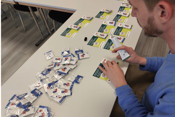 Hände kleben Inklusions-Schleifen auf Postkarten