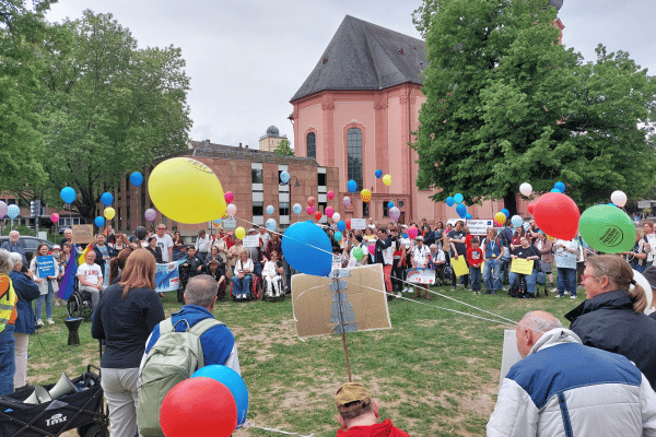 Viele Menschen mit bunten Luftballons und Schildern bei der Mahnwache