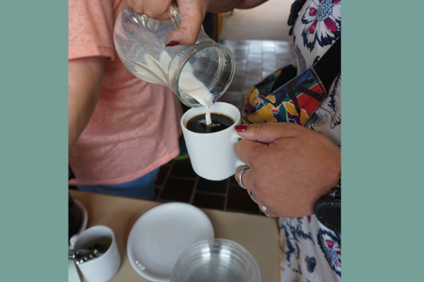 Eine Frau schenkt sich Milch in den Kaffee.