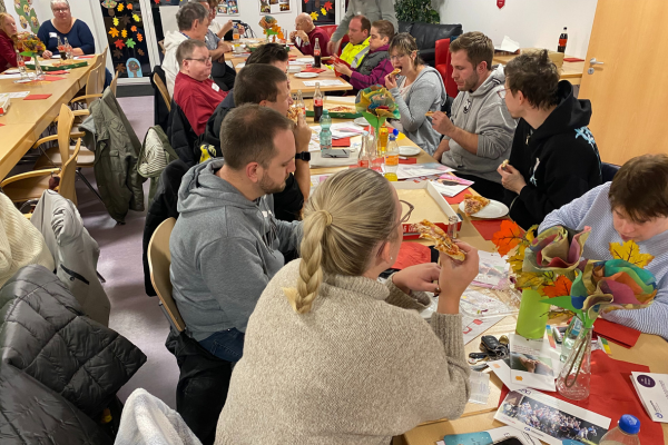 Menschen sitzen am Tisch und essen Pizza