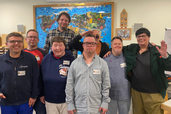 Acht Personen lachen und winken in die Kamera