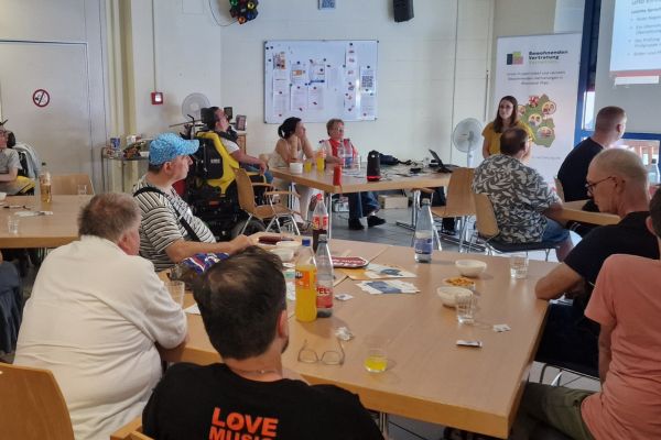Mehrere Personen sitzen an Tischgruppen in einem Raum