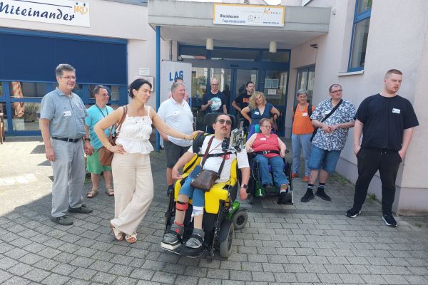 Eine Gruppe von Menschen stehend und im Rollstuhl vor dem Eingang zur Nieder-Ramstädter Diakonie